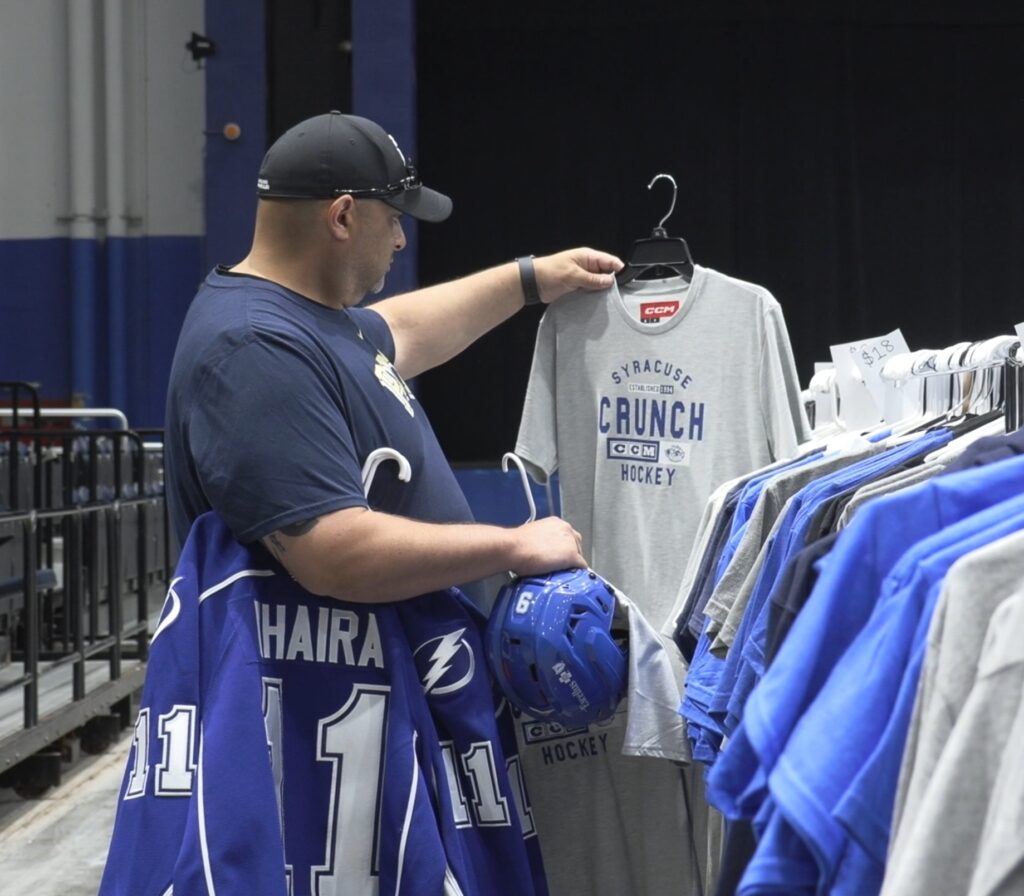 A man holding and looking at a T-shirt. 